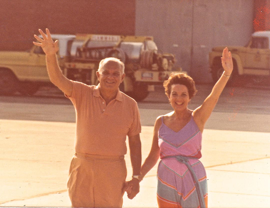 Gramie and Grandad waving to the camera in an unknown airfield